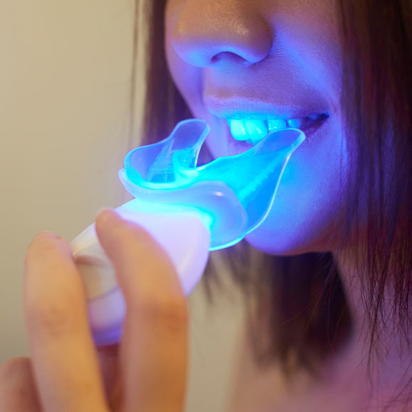 Girl holding LED teeth whitening device 